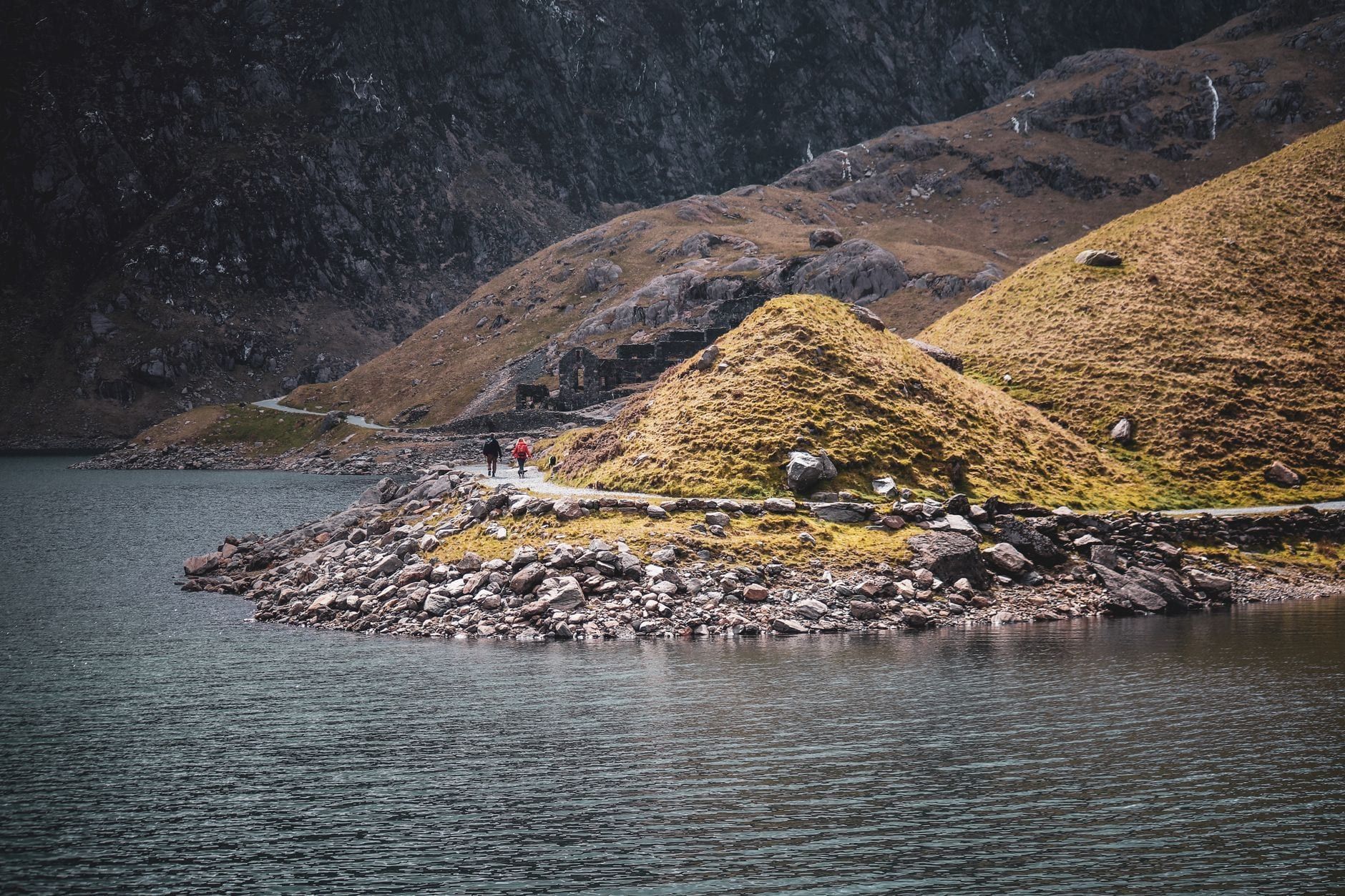 Wanderer gehen auf einem Pfad neben einem Bergsee im Snowdonia-Nationalpark.