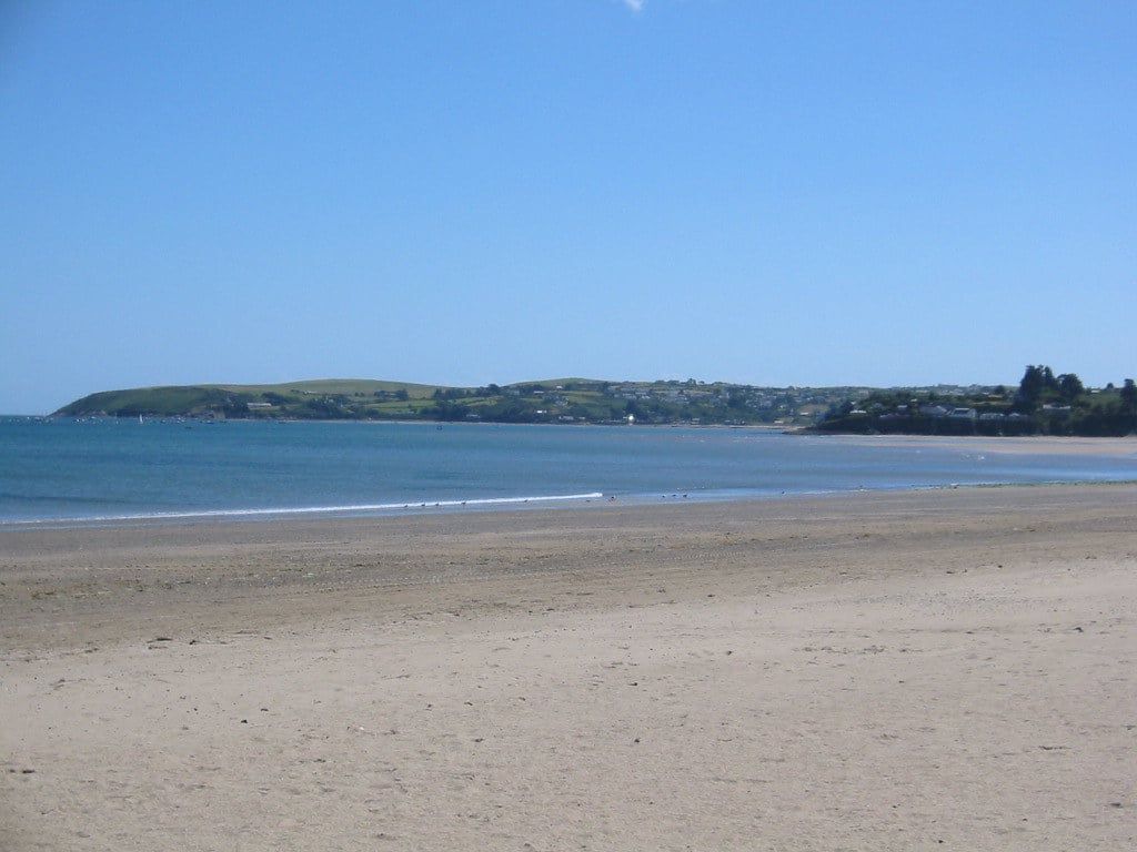 Ein breiter Sandstrand trifft auf das ruhige Wasser der Bucht von Abersoch unter klarem blauem Himmel auf der Lleyn-Halbinsel.