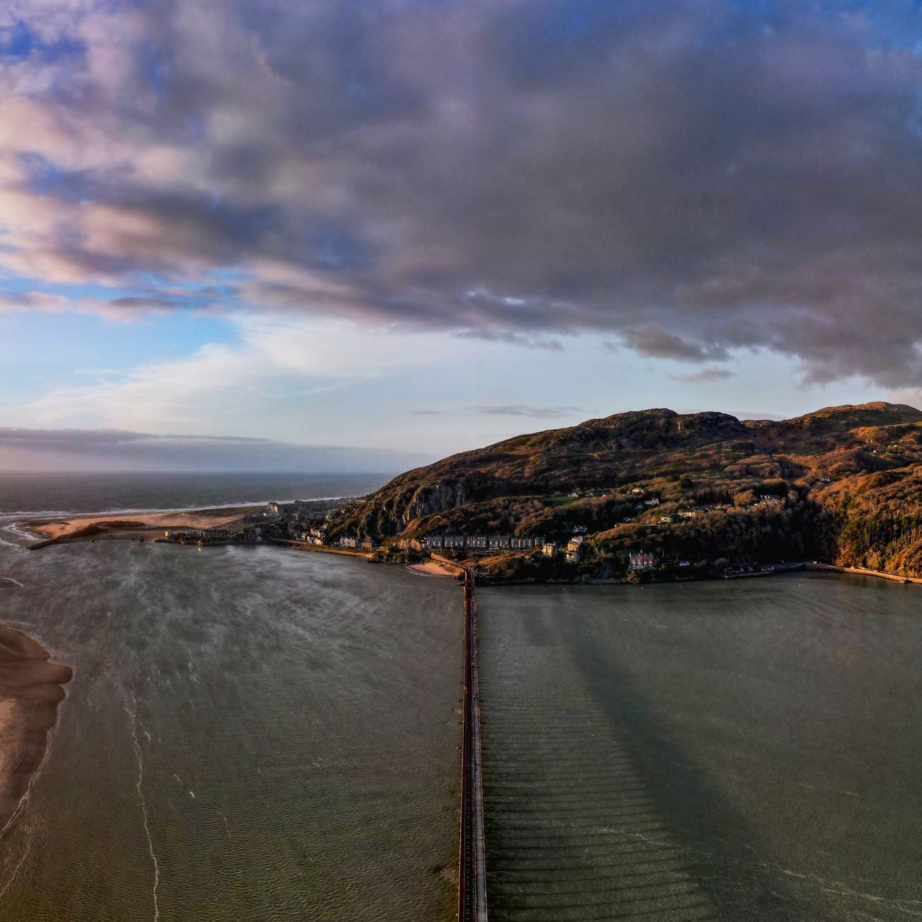 Luftaufnahme der Eisenbahnbrücke von Barmouth über das Mawddach-Ästuar, mit Blick auf den Ort und die Küstenhügel von Snowdonia.