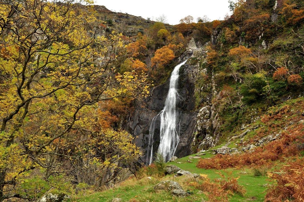 Aber Falls cascades down a rocky cliff framed by autumn foliage in Snowdonia.