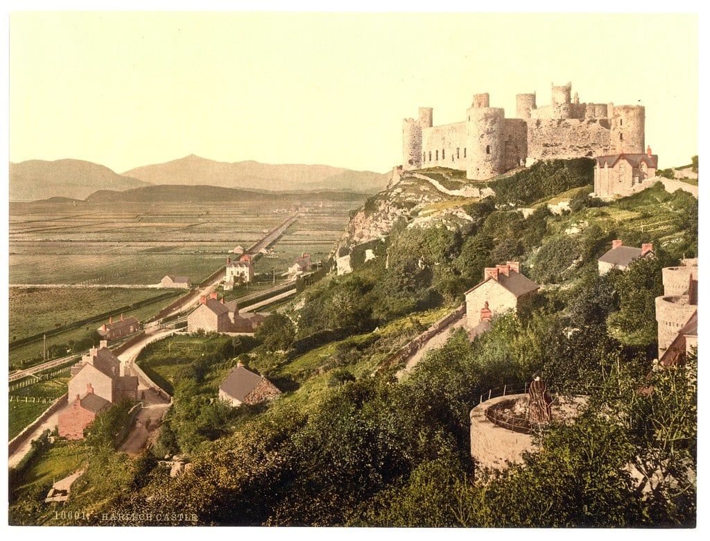 Harlech Castle perched atop a rocky cliff overlooking the coastal plain and distant mountains of Snowdonia.